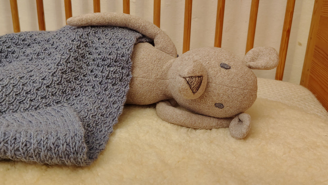 Handgefertigter Stofftier Bär aus Baumwollfleece zugedeckt mit einer Babydstrickdecke aus Merinowolle